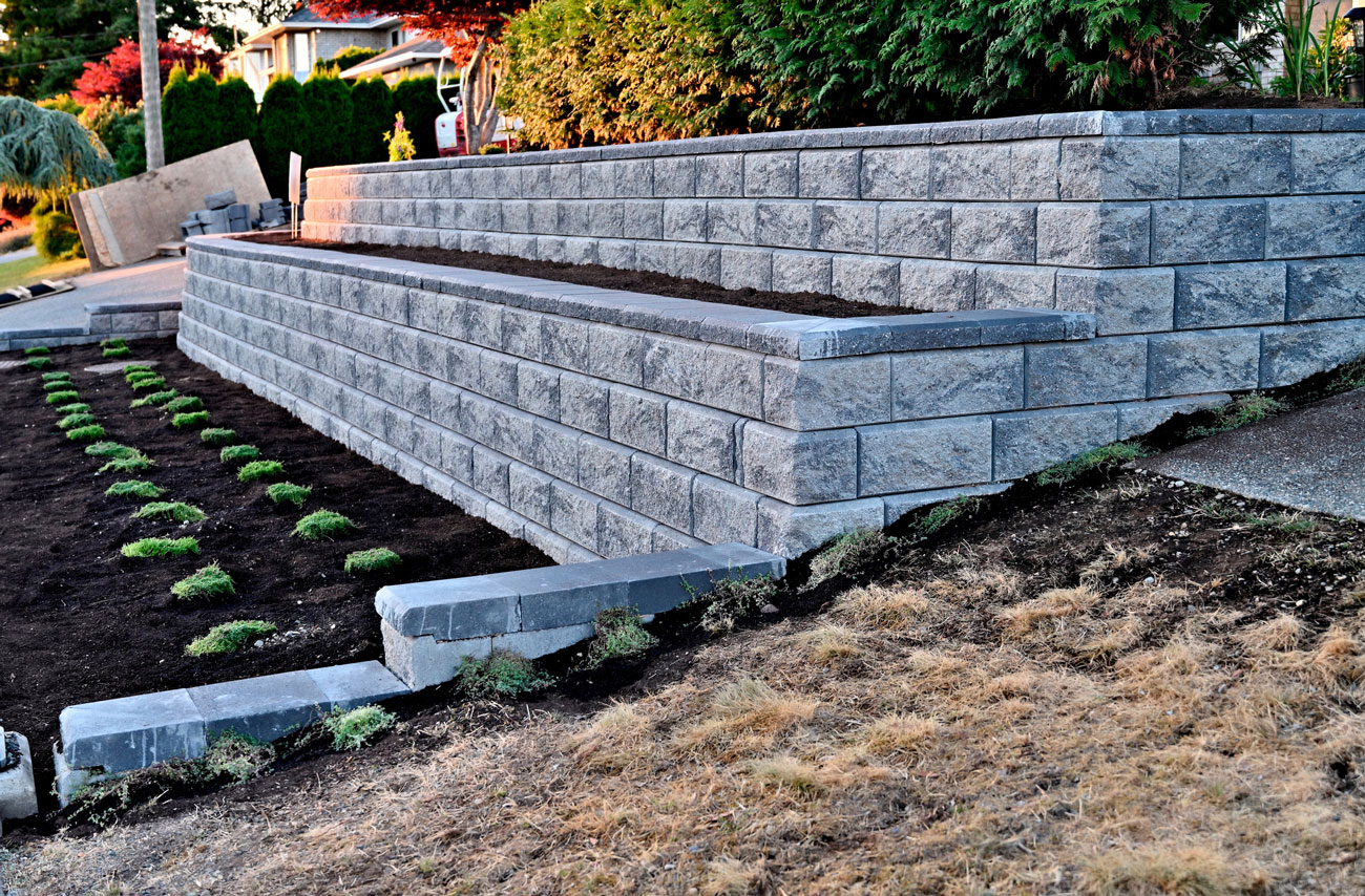 Tiered gray block retaining wall with a planted terrace and fresh landscaping