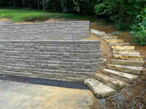 A close-up of a stone retaining wall with a set of flat stone steps next to it.